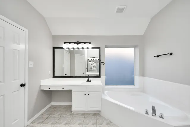 a bathroom with a bathtub a sink and a mirror