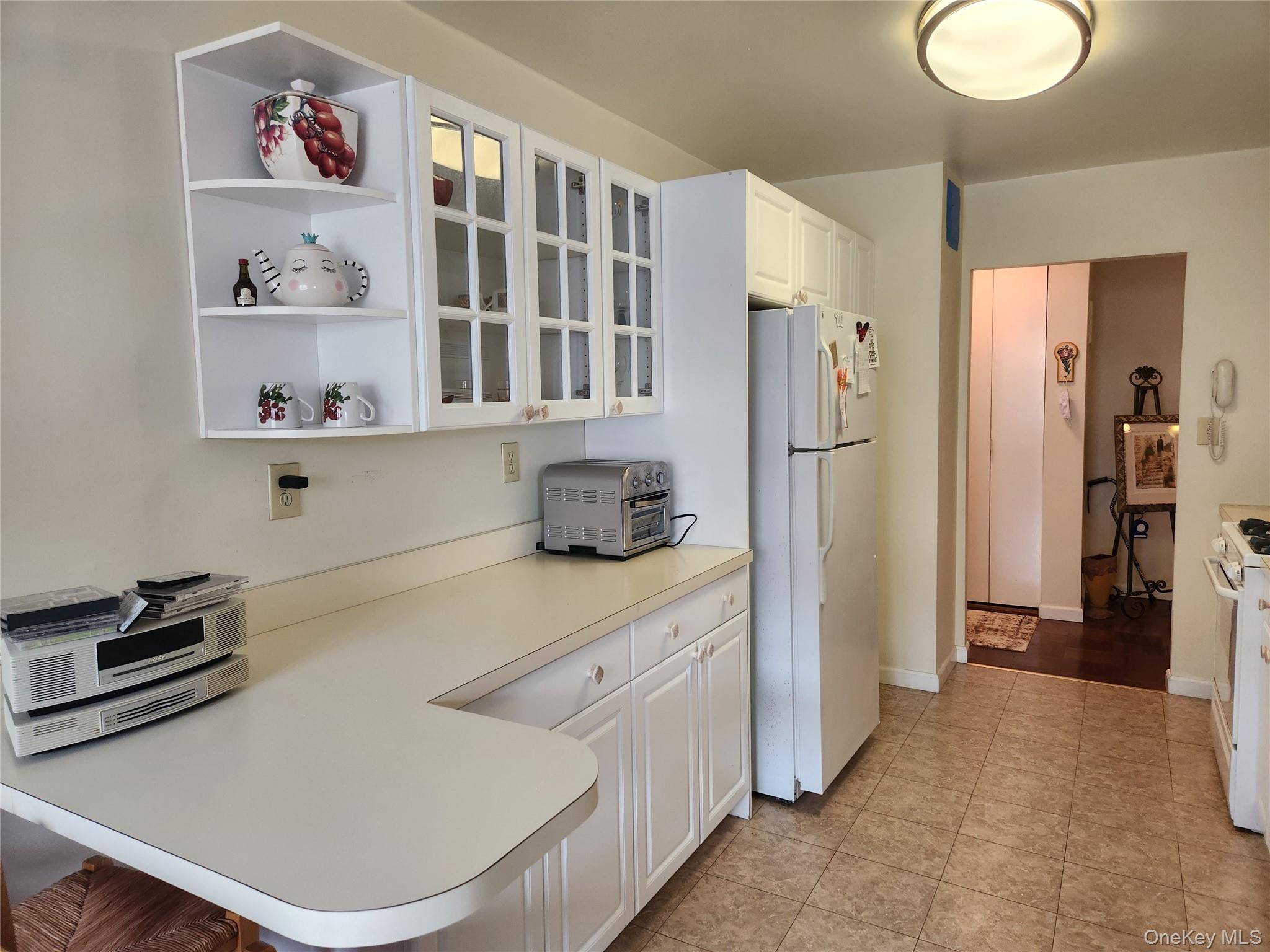 700 Shore Road, Unit 4K Long Beach, NY 11561 - Photo 12 of 32 Kitchen featuring white cabinets, light countertops, white appliances, a peninsula, and open shelves
