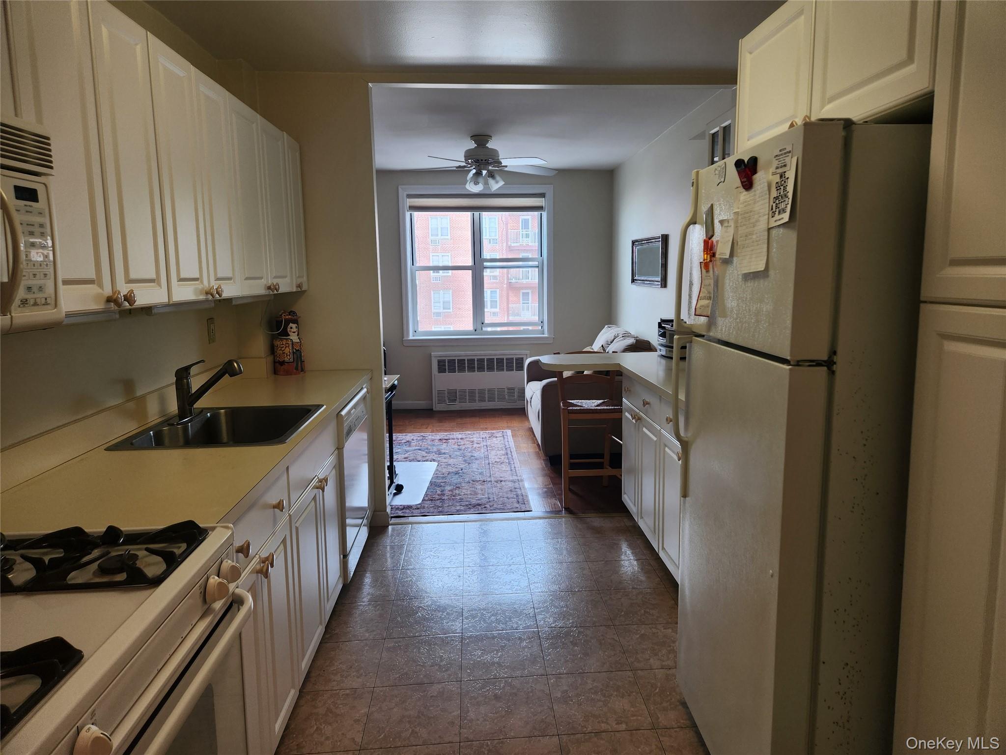 700 Shore Road, Unit 4K Long Beach, NY 11561 - Photo 13 of 32 Kitchen with white appliances, light countertops, heating unit, and white cabinetry