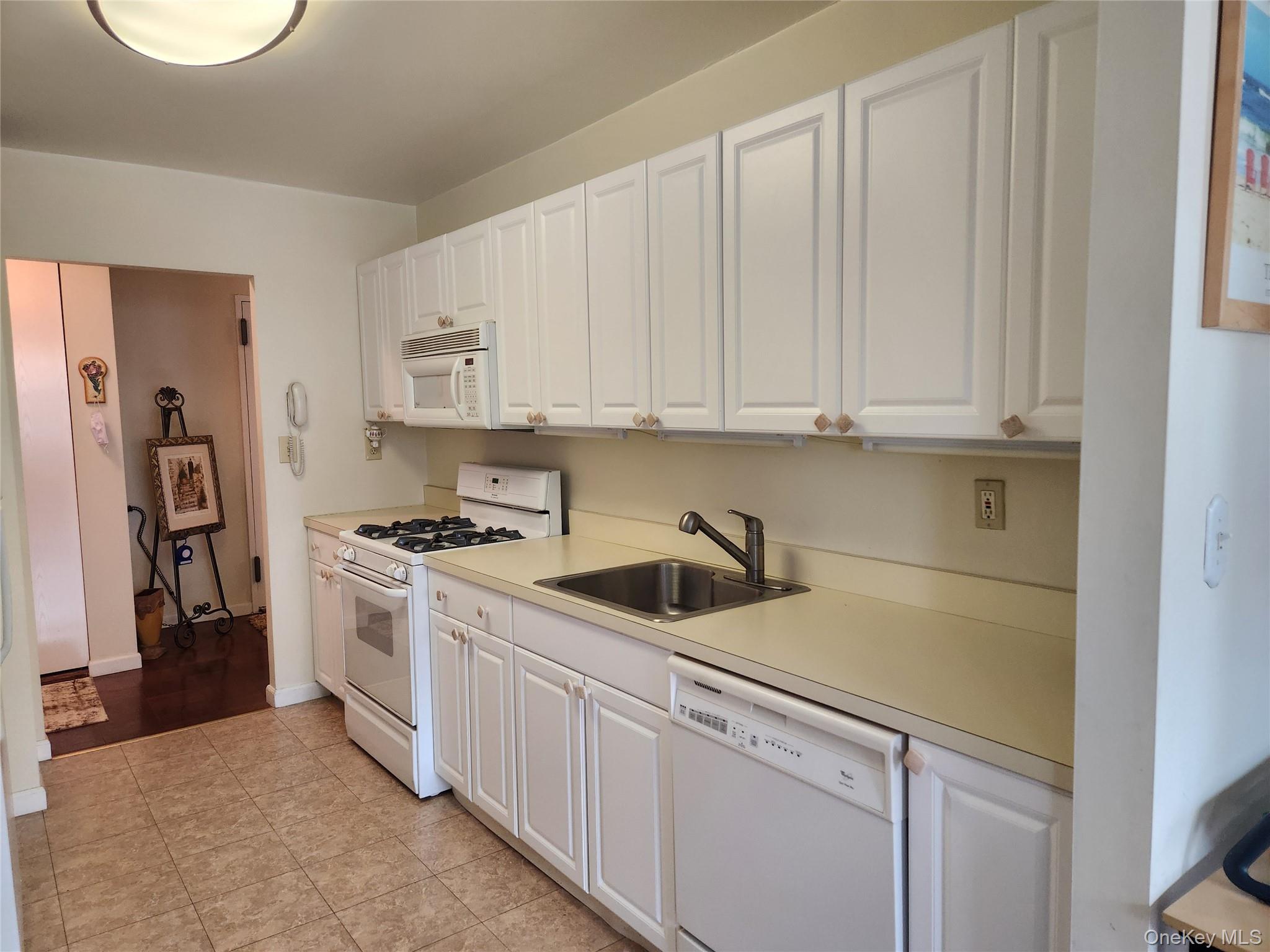 700 Shore Road, Unit 4K Long Beach, NY 11561 - Photo 10 of 32 Kitchen with white appliances, white cabinetry, counter-tops, and light tile patterned flooring