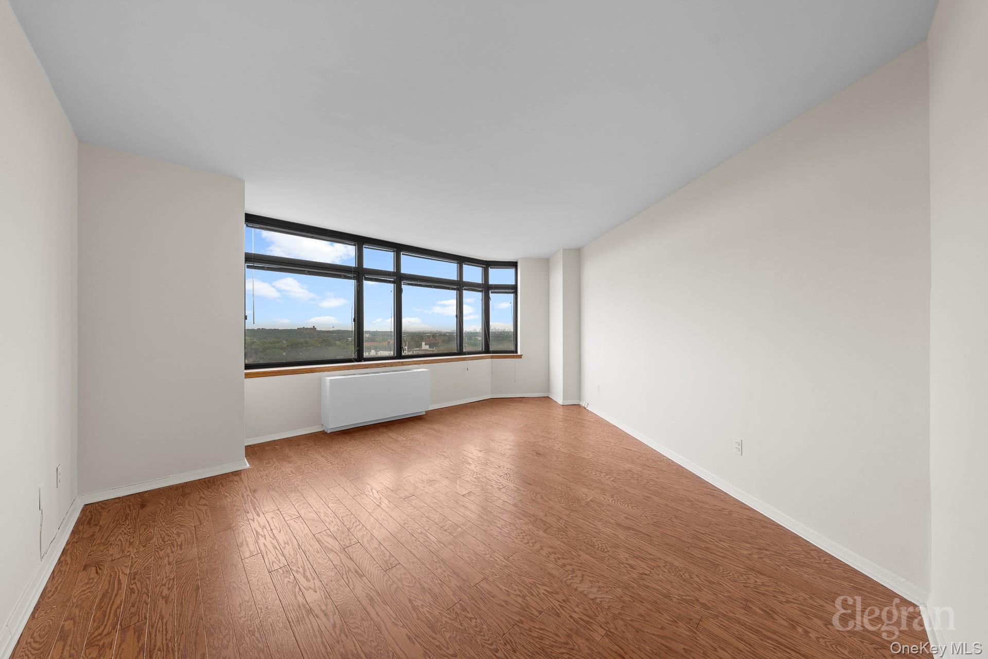 11201 Queens Boulevard, Unit 16F Queens, NY 11375 - Photo 5 of 24 an empty room with wooden floor and windows