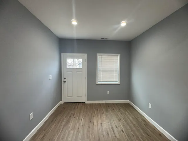 an empty room with wooden floor and window