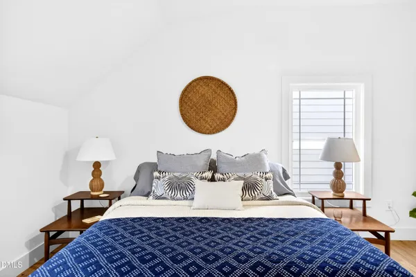 a bedroom with a bed and a lamp on dresser