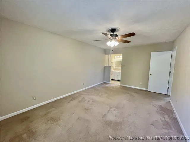 an empty room with a chandelier fan and windows
