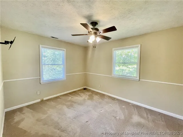 an empty room with windows and fan
