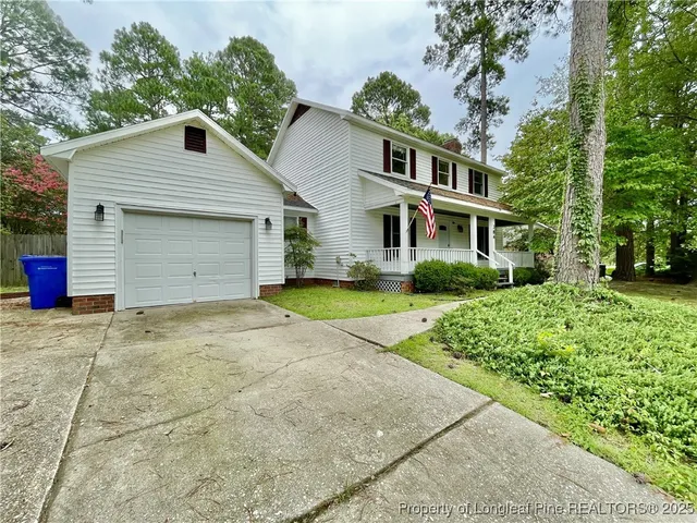 a front view of house with yard and trees in the background