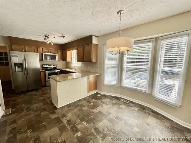 a kitchen with stainless steel appliances granite countertop a refrigerator a stove a sink and a microwave