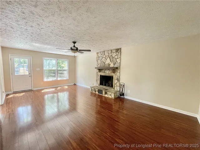 an empty room with wooden floor fireplace and windows