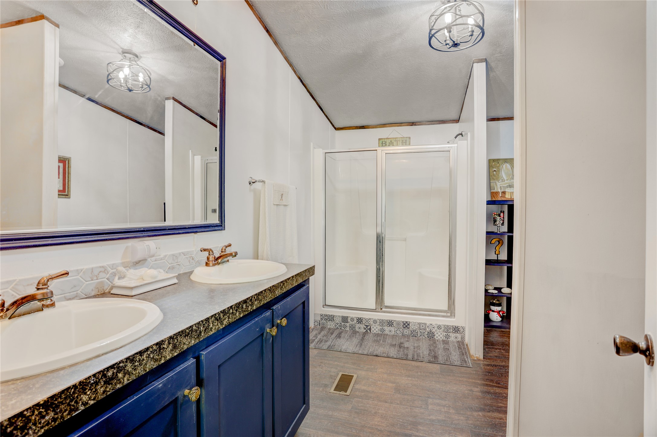 2811 Pisces Street Rosenberg, TX 77469 - Photo 19 of 34 Stylish bathroom with double vanity, dark countertops, blue cabinets, large mirror, and enclosed shower.