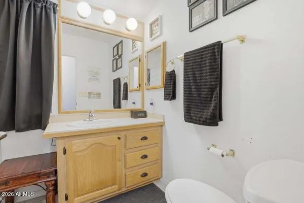 a bathroom with a granite countertop sink toilet mirror and a shower