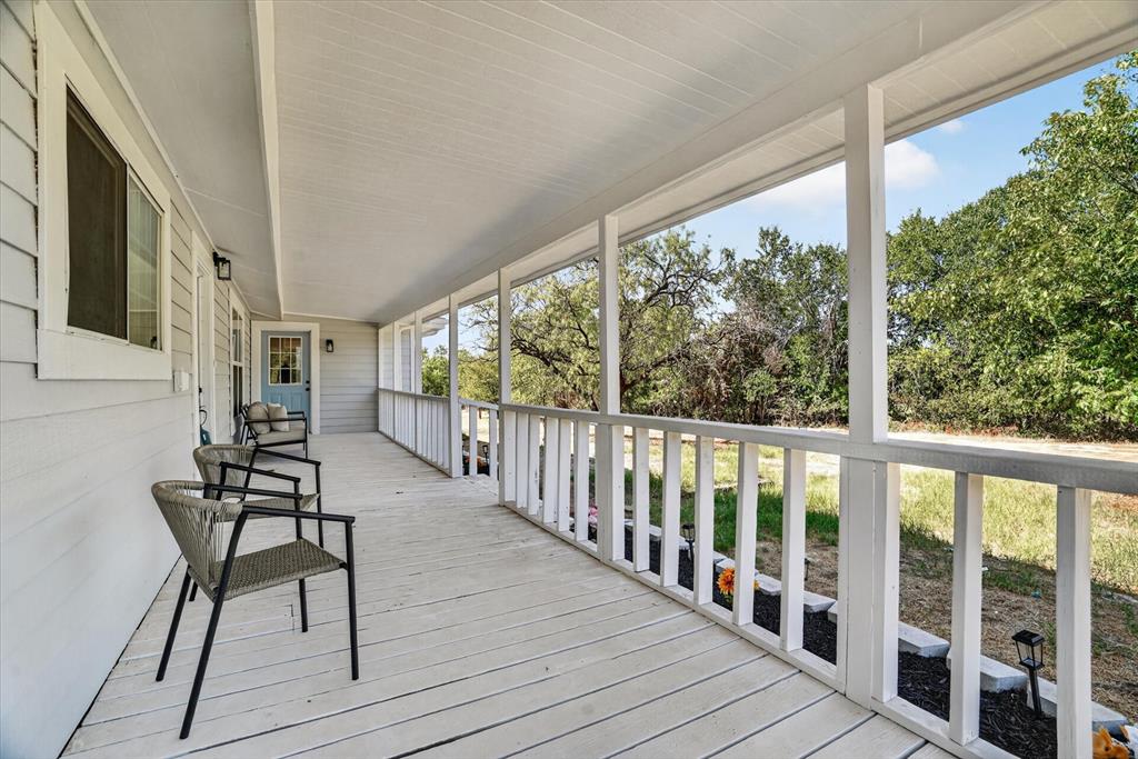 795 Meadow Road Springtown, TX 76082 - Photo 2 of 25 Expansive covered porch with wood-finish flooring, white railing, and a light blue entry door