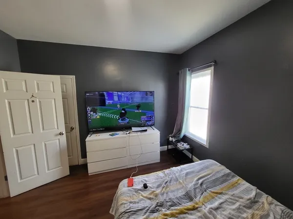 a bedroom with a bed and a flat tv screen on the dresser
