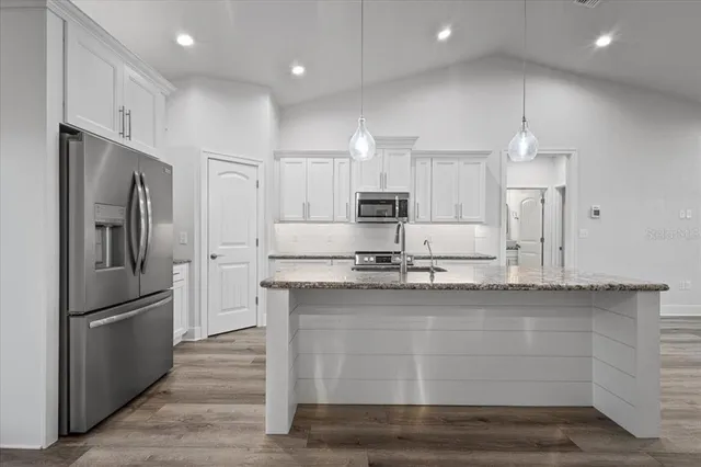 a kitchen with kitchen island white cabinets and stainless steel appliances