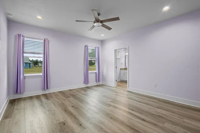 an empty room with wooden floor and a ceiling fan