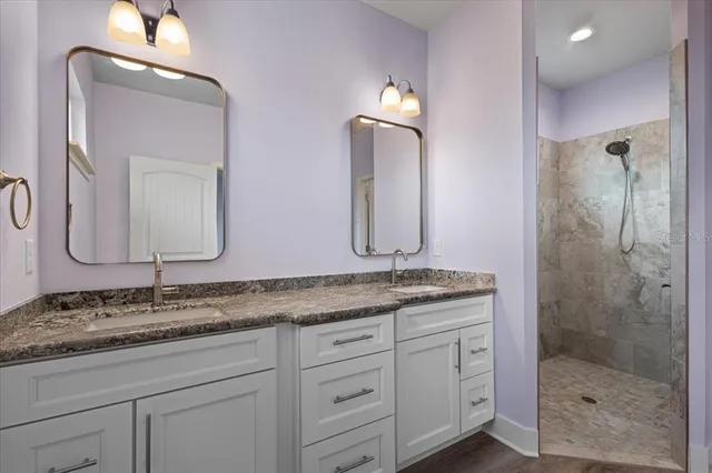 a bathroom with a granite countertop double vanity sink and mirror