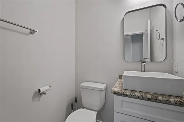 a bathroom with a granite countertop toilet sink and mirror