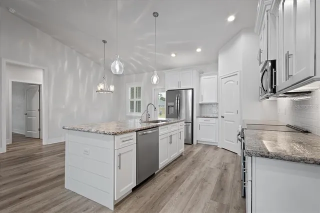 a large kitchen with granite countertop a large counter top a sink stainless steel appliances and cabinets