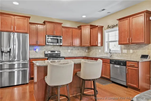 a kitchen with stainless steel appliances granite countertop a stove a sink a microwave a refrigerator and white cabinets