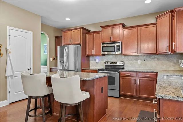 a kitchen with stainless steel appliances granite countertop a stove top oven a refrigerator a sink and a microwave