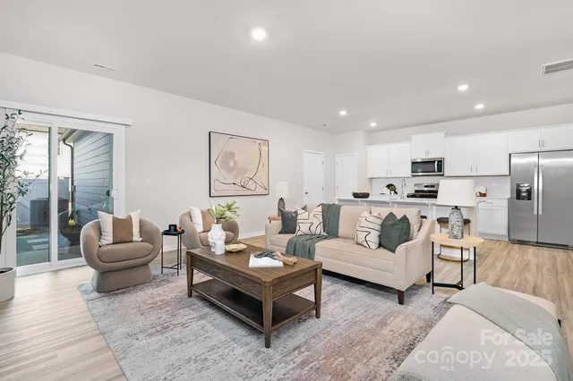 a living room with furniture white walls and kitchen view