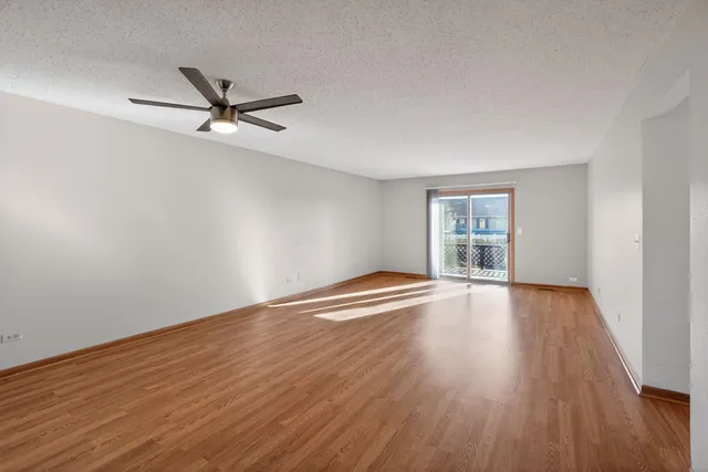an empty room with wooden floor fan and windows