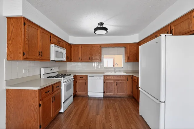 a kitchen with stainless steel appliances granite countertop a refrigerator a sink dishwasher a stove with wooden cabinets and floor