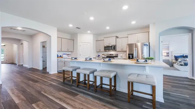a kitchen with stainless steel appliances a dining table chairs microwave and cabinets