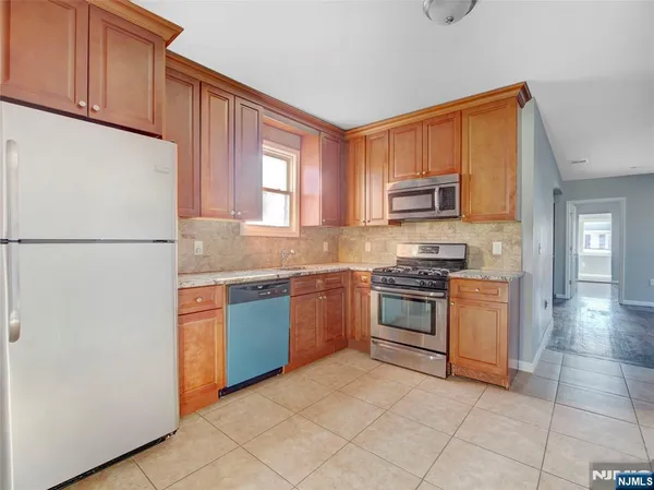 a kitchen with granite countertop a refrigerator stove top oven and sink