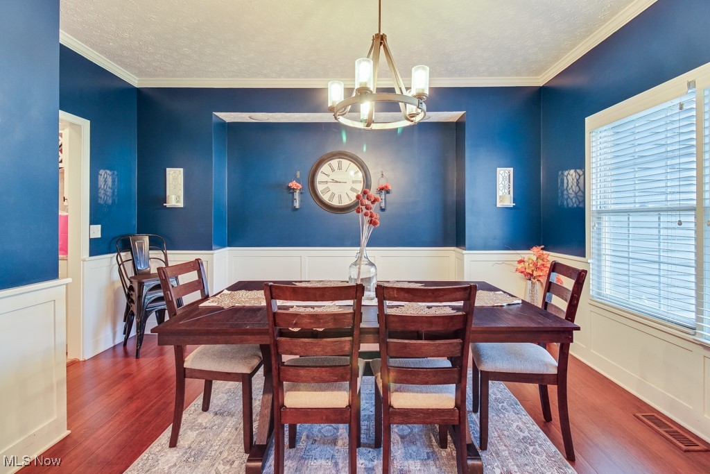 132 Timber Ridge Drive, Unit RDR Elyria, OH 44035 - Photo 4 of 41 Dining room featuring crown molding, a textured ceiling, hardwood / wood-style flooring, and a notable chandelier