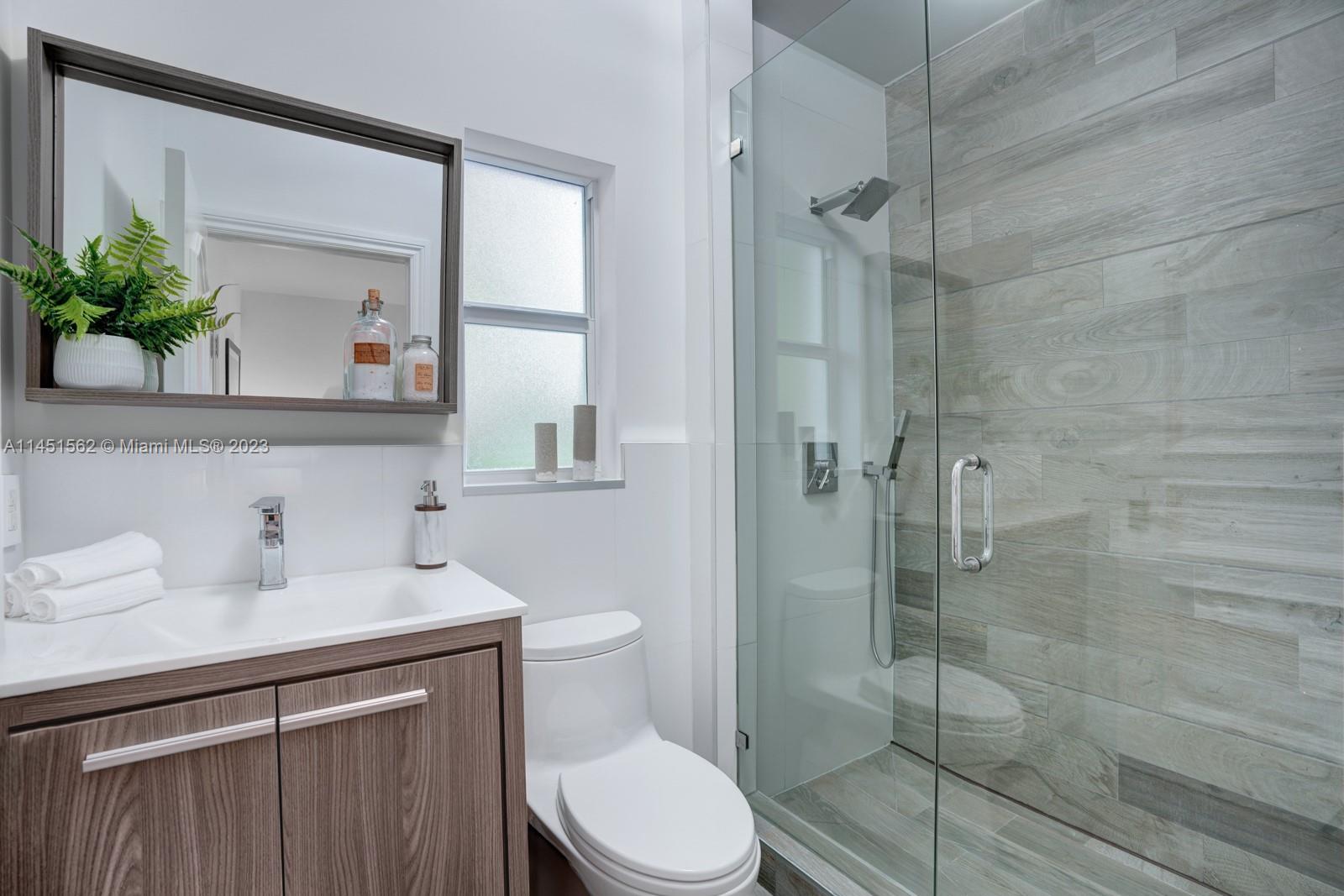 761 Buttonwood Lane Miami, FL 33137 - Photo 32 of 64 a bathroom with a sink a mirror a potted plant and a toilet