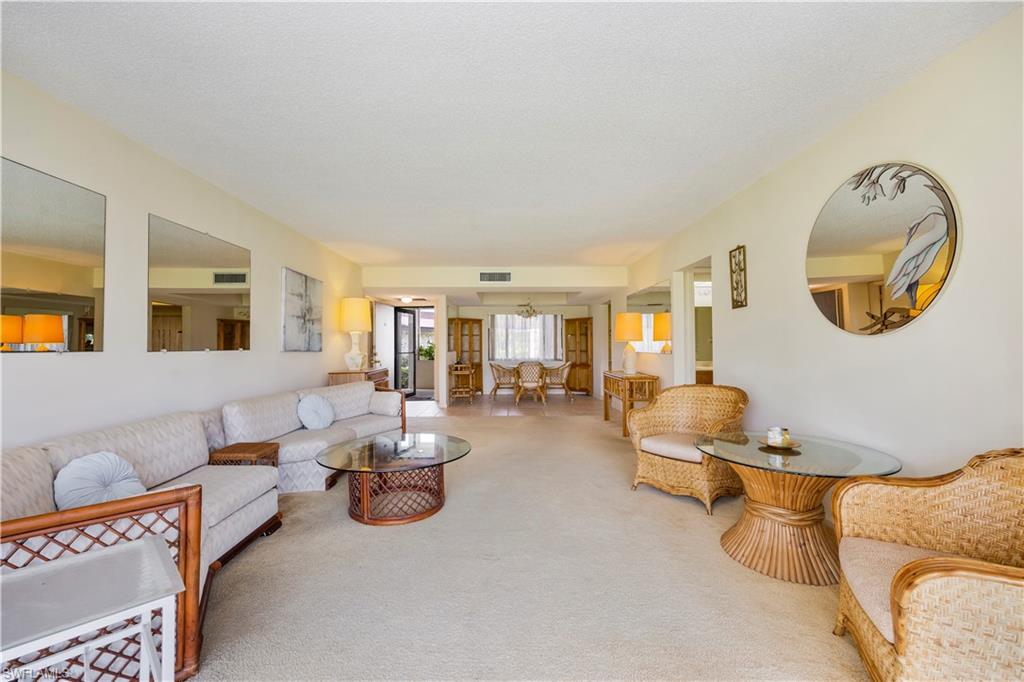 415 Augusta Boulevard, Unit 110 Naples, FL 34113 - Photo 17 of 31 a living room with furniture and a mirror
