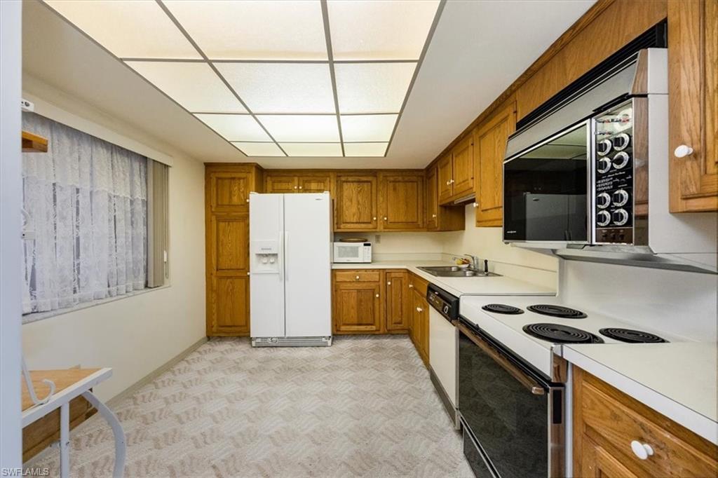 415 Augusta Boulevard, Unit 110 Naples, FL 34113 - Photo 21 of 31 a kitchen with stainless steel appliances granite countertop a stove a sink dishwasher and a refrigerator