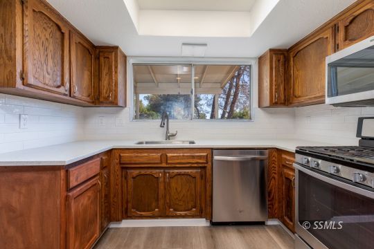 718 Sonja Avenue Ridgecrest, CA 93555 - Photo 10 of 33 a kitchen with stainless steel appliances granite countertop a sink a stove and a microwave
