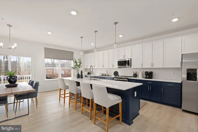 a kitchen with stainless steel appliances a dining table chairs refrigerator and sink