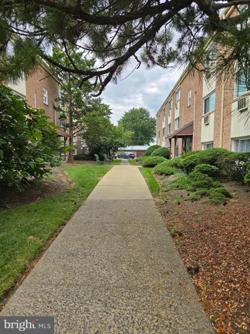 a view of a brick house next to a yard with big trees