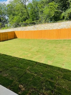 174 Balmorhea Street Kyle, TX 78640 - Photo 29 of 29 A spacious backyard with a fresh green lawn offers privacy and room for outdoor enjoyment.