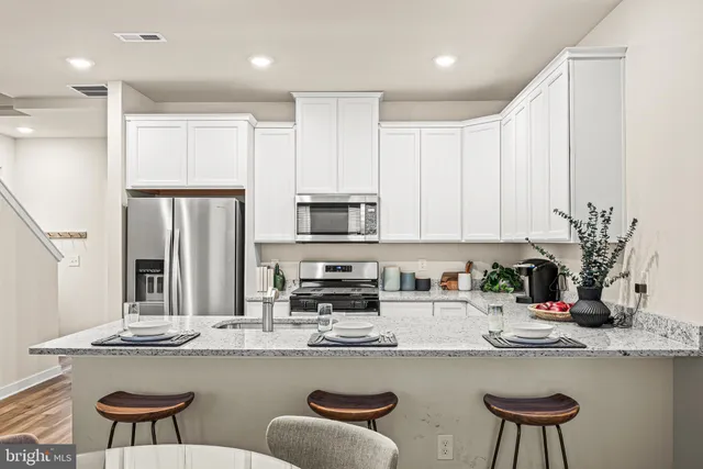 a kitchen with stainless steel appliances granite countertop a kitchen island a stove a table and chairs in it