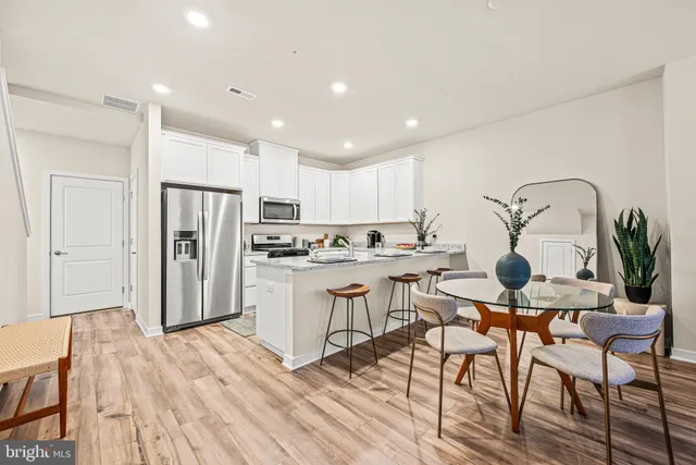 a living room with stainless steel appliances kitchen island granite countertop a dining table chairs and sink
