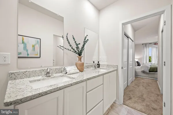 a en suite bathroom with a granite countertop sink and a mirror