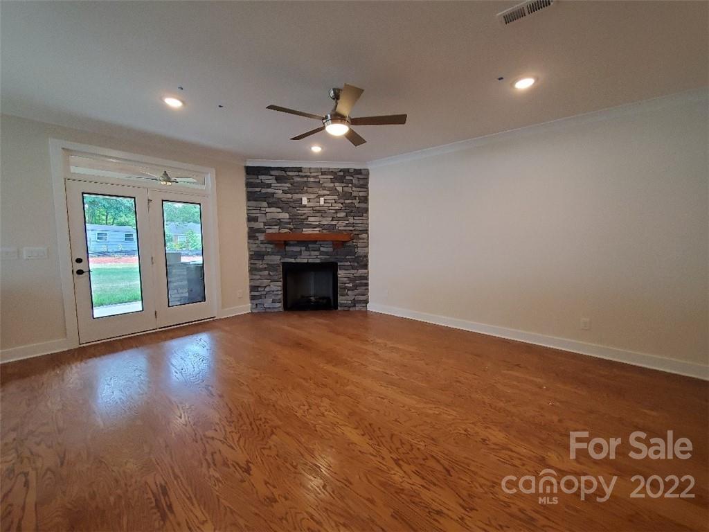 5201 Valley Stream Road Charlotte, NC 28209 - Photo 2 of 17 an empty room with wooden floor fireplace and windows