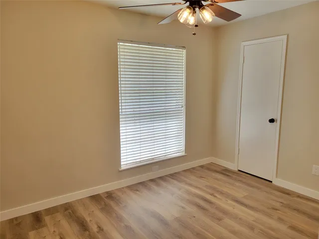 an empty room with a window and a chandelier fan