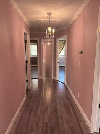 a view of a hallway with wooden floor and a chandelier