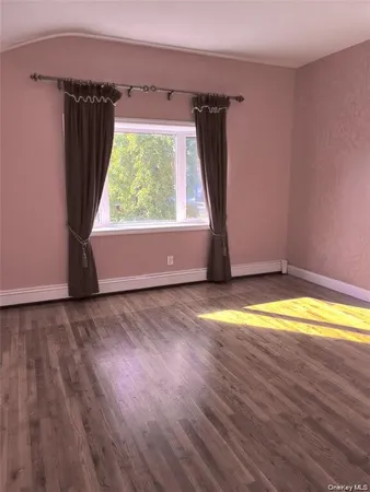 an empty room with wooden floor and a window