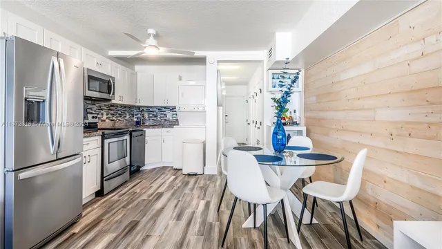 a kitchen with stainless steel appliances a dining table chairs refrigerator and sink