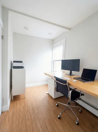 a view of a workspace with furniture and a window