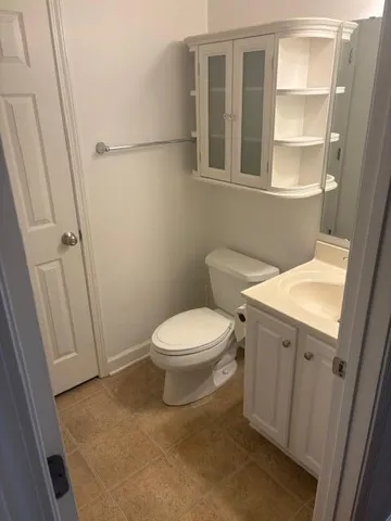 a white toilet sitting next to a bathroom sink and vanity