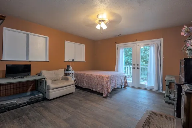 a spacious bedroom with a bed and a flat tv screen on dresser