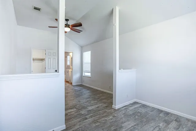 an empty room with wooden floor cabinet and windows