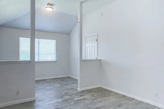 an empty room with wooden floor and windows