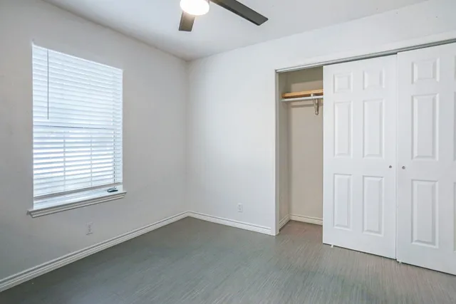 an empty room with wooden floor closet and windows